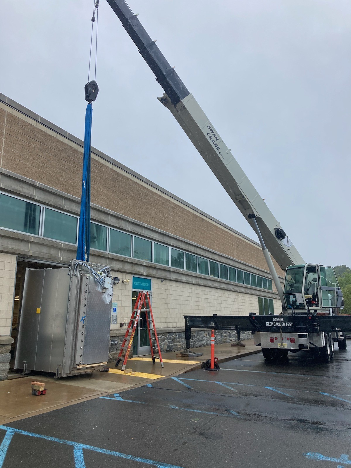 Swan Crane Service rentable crane aiding in installation of HVAC system